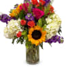 Colorful bouquet with roses, hydrangeas, and a sunflower in a glass vase