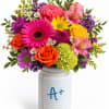 Colorful mixed bouquet in a white jar vase with an A+ design