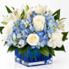 White roses and lilies with blue hydrangeas in a blue glass vase