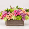 Mixed bouquet of pink, peach, and green flowers in a wooden box