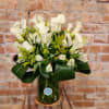 White calla lilies and small white blooms in a glass vase