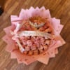 Pink rose bouquet with a gold crown and ribbon on pink wrapping