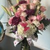 Tall pink and white mixed flower arrangement in a glass vase with ribbon and butterfly decoration