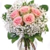 Round glass vase of pink roses surrounded by white filler flowers in a compact bouquet