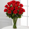 Tall clear vase filled with long-stemmed red roses.