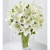 Tall arrangement of white lilies in a clear glass vase