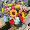 Mixed bouquet with sunflowers, roses, lilies, and hydrangeas in a glass vase