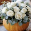 White roses arranged in a carved pumpkin centerpiece