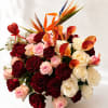 Bouquet of red, pink, and white roses with orange calla lilies in a white vase