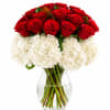 Red roses and white hydrangeas in a clear glass vase