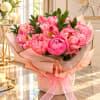Pink peony bouquet wrapped in blush paper with a ribbon