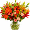 Orange roses and lilies in a clear glass vase