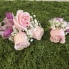 Two small pink rose corsages with white baby's breath and ribbon