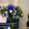 Blue and white funeral spray on a casket with ribbon streamers