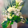 White floral arrangement with calla lilies and orchids in a tall vase