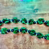 Green and dark blue beaded garland laid on a wooden surface