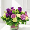Pink roses and purple flowers arranged in a square glass vase