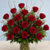 Deep red roses with lush green foliage and white accents, arranged upright