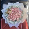 Bouquet of pink roses with white baby's breath in pale wrapping