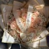 Bouquet of pale pink roses wrapped in cream paper with satin ribbons