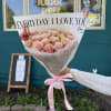 Bouquet of pink and peach roses wrapped in white paper with a pink ribbon