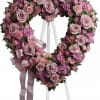 Heart-shaped pink and lavender floral wreath on an easel with ribbon