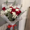 Bouquet of red roses and white daisies wrapped in white paper with a red ribbon