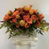 Orange floral arrangement in a white pedestal vase