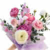 Handheld bouquet of pink, purple, and white ranunculus with lavender wrap