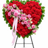 Heart-shaped floral standing arrangement with red carnations and pink roses on an easel