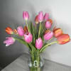 Pink and orange tulips arranged in a clear glass vase