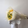 Bouquet of yellow roses and pale flowers wrapped in cream paper