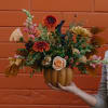 Autumn floral arrangement in a pumpkin-shaped vase with roses and mums