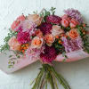 The bouquet is elegantly cradled in premium blush-pink frosted wrapping with subtle