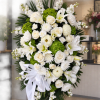 White floral standing spray with roses, lilies, and green hydrangeas