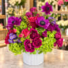 Bright magenta and purple bouquet in a white ribbed vase