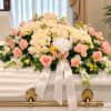 Large white and pink rose spray on a casket with a white ribbon