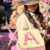 Woman holding a pink box filled with cream and pink roses