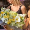 Woman holding a large bouquet of white and yellow flowers