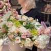 Woman holding a large pastel flower arrangement in a round box