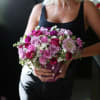 Woman holding a pink and purple bouquet in a vase