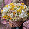 Large bouquet of white orchids, yellow orchids, and pale roses in a pink wrap