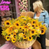 Large basket of sunflowers and yellow roses held by a woman