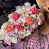 Large pastel bouquet with pink, white, and lavender flowers beside a teddy bear