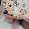 Bride holding a pastel bouquet of roses, ranunculus, and white blossoms