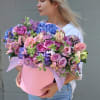 Large mixed bouquet in a pink hat box with pink, purple, and blue flowers