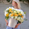 Woman holding a large bouquet of white and yellow flowers in a silver box