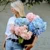 Woman holding a large bouquet of blue and pink hydrangeas