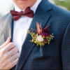 Boutonniere with burgundy and blush flowers on a suit jacket