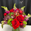 Red roses and purple flowers in a glass vase with red ornaments
